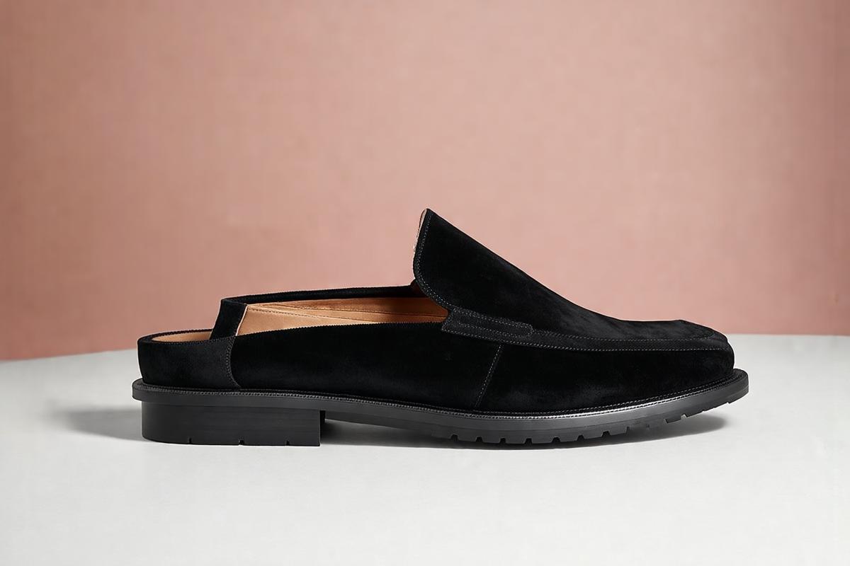Sapatos femininos mule de couro preto com salto bloco em close up mostrando acabamento
