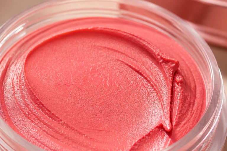 Close em um blush cremoso de alta qualidade, destacando a textura do produto em um ambiente de maquiagem bem iluminado.